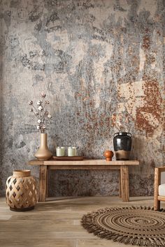 a table with two vases sitting on top of it next to a wall covered in peeling paint