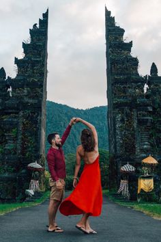 a man and woman are dancing in front of an entrance to a jungle like area