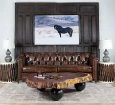 a living room with leather couches and a horse painting on the wall behind it