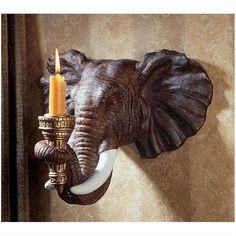 an elephant head mounted to the side of a wall with a candle in it's trunk