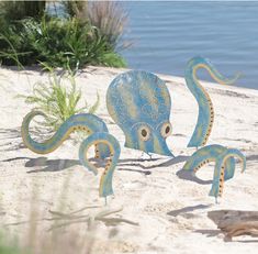 two blue octopus sculptures sitting on top of a sandy beach