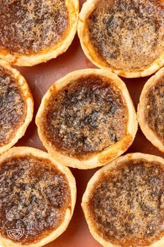 many small pies are sitting on a table top with some brown stuff in the middle