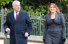 a man and woman dressed in business attire walking down the street with trees behind them