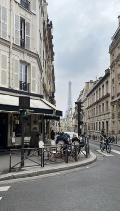 an empty street with people sitting at tables in front of the eiffel tower