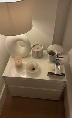 a white table topped with a lamp next to a cup