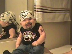 a baby sitting on top of a toilet in front of a mirror with his mouth open