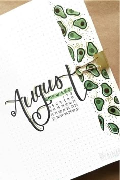 an open notebook with the word august written in cursive writing and green avocados on it