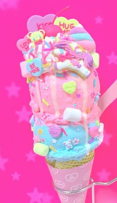 an ice cream cone with pink and blue frosting on top, surrounded by stars