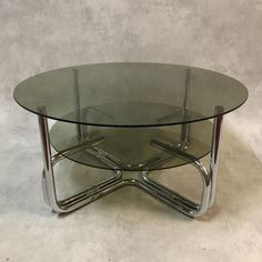 a glass table with metal legs on a white floor and wall in the back ground