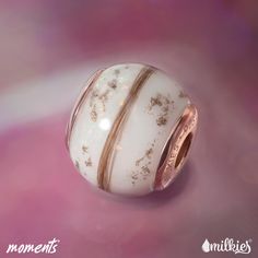 a white bead with gold stripes and stars on it's side sitting on a pink surface