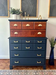 a blue dresser with gold handles and drawers in front of two pictures on the wall