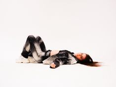 a woman is laying on the floor with her hair blowing in the wind while wearing black and white clothes