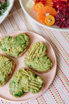 small sandwiches with guacamole on a pink plate next to bowls of salad