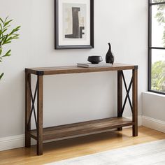 a wooden table sitting in front of a window next to a vase on top of a hard wood floor