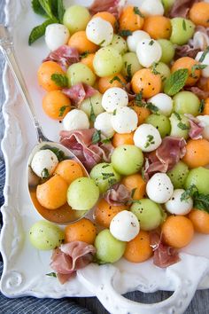 a white plate topped with oranges, grapes and mozzarella sprinkled with mint