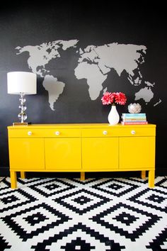 a yellow dresser in front of a black and white wall with a world map on it