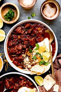 two bowls filled with chili and tortilla chips on top of a black table