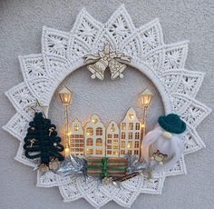 a white doily hanging on the wall with christmas decorations and lights in front of it