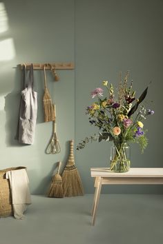 a vase filled with flowers sitting on top of a wooden table next to a broom