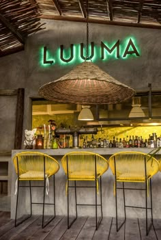 three yellow chairs sitting in front of a bar