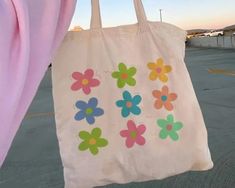 a bag with flowers painted on it hanging from a pink curtain in an empty parking lot