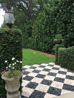 a checkerboard pattern is on the ground in front of some bushes and flowers