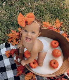 a baby sitting in a tub filled with foamy water and pumpkins on the ground