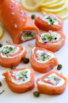 salmon and capers wrapped in cream cheese on a white plate with lemon wedges