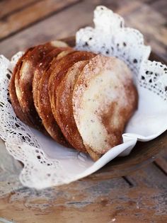 several pastries are sitting on a white doily in a wooden bowl with lace