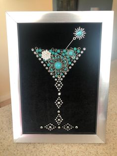 an art piece with beads and jewels on display in a silver framed glass frame,