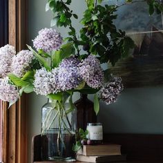 a vase filled with purple flowers sitting on top of a table next to a window