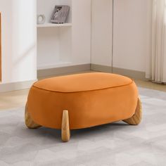 an orange ottoman sitting on top of a white rug