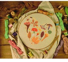 an embroidery kit with leaves, yarn and needles laid out on a wooden table next to it