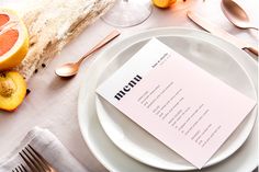 a white plate topped with a piece of paper next to oranges and silverware