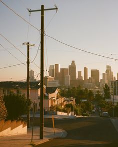 the city skyline is seen in the distance with power lines running across it and telephone poles on either side