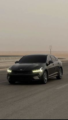 a black car driving down the road with fog in the air behind it and an orange light at the top