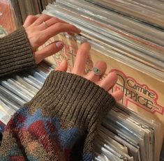 a woman's hand reaching for a ring on top of records