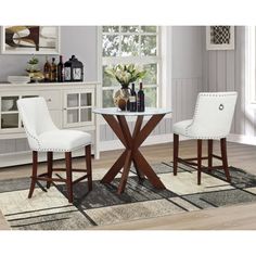 two white chairs sitting at a table in a living room with a rug on the floor