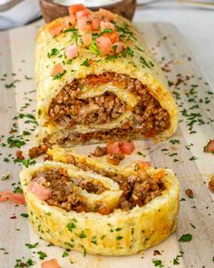 a meat and cheese roll cut in half on a cutting board