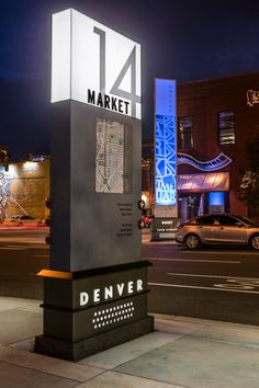 a large sign on the side of a road in front of some buildings at night