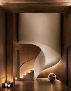 a spiral staircase in the middle of a room with candles on the floor and light coming from above