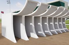 a row of white benches sitting next to each other on top of a dirt field