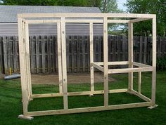 a wooden structure sitting in the middle of a yard next to a fence and grass