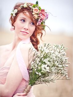 a woman with flowers in her hair is holding a flower bouquet and wearing a pink dress