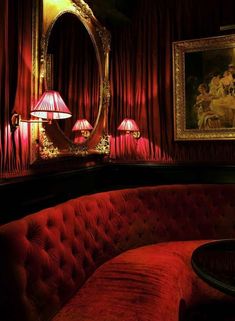 a red couch sitting in front of a mirror on top of a wooden table next to a lamp