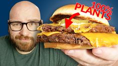 a man holding up a large hamburger with cheese on it and the words 100 % plans