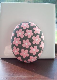 a button with pink flowers on it sitting on a wooden table next to a window