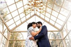 a man and woman standing in front of a chandelier with their arms around each other