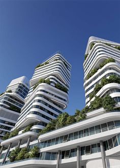 two tall buildings with plants growing on the top and bottom, against a blue sky