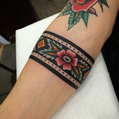 a woman's arm with a tattoo on it that has flowers and leaves on it